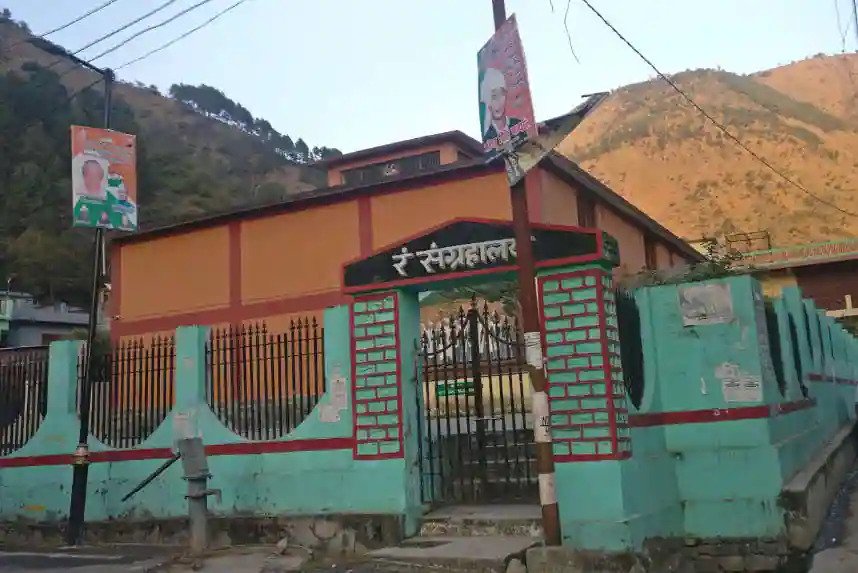 The Rung Museum building in Dharchula, with its signage in Hindi and the hills above the Kali river behind it