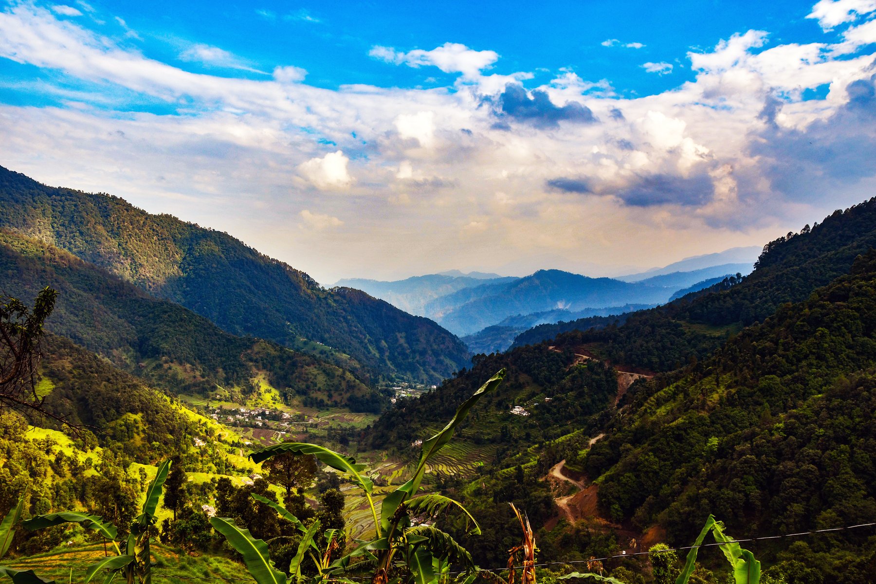 Terraced green farmland and a village tucked into the Gori Ganga valley near Madkote, mountains behind