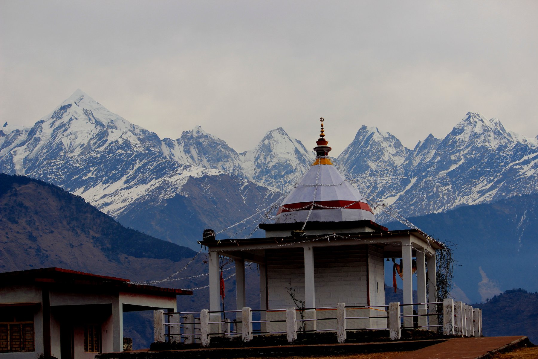Nanda Devi Temple's prayer-flag-draped dome with the snow-capped Panchachuli range rising behind it